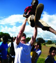 male volunteer creighton university lifting a child