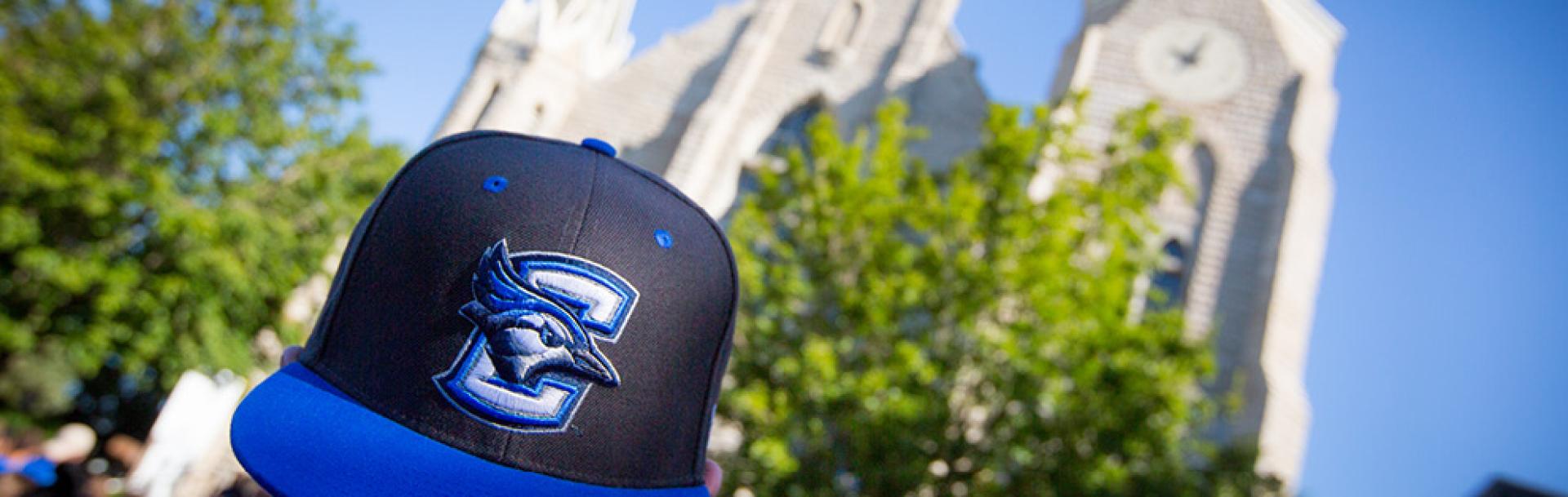 Student wearing Creighton Bluejays baseball cap on campus.