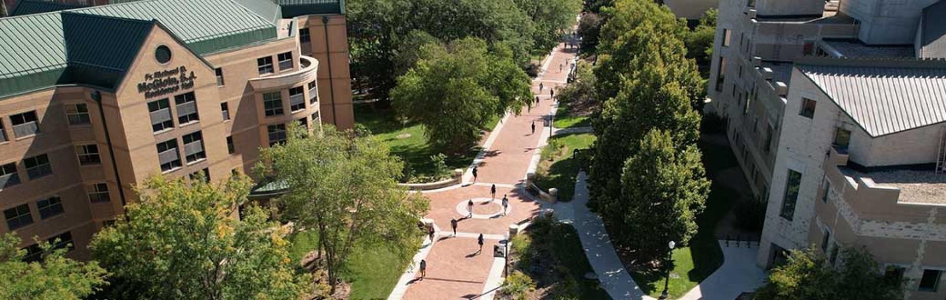 Bird's eye view on sunny day of people walking down Creighton mall past McGloin Residence Hall.