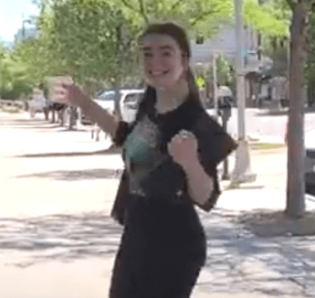 Jacey Greco walking down street smiling on sunny day.