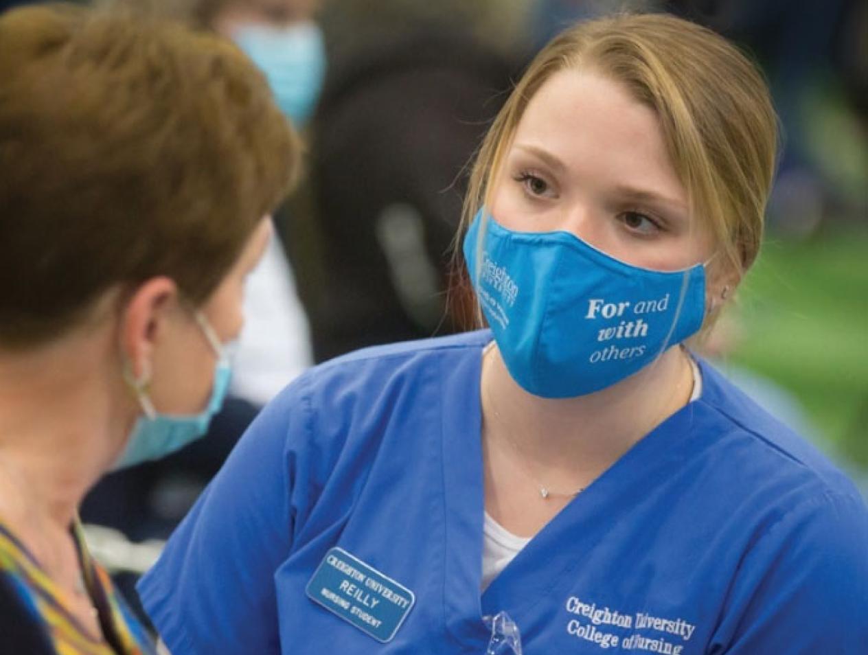 Nursing student working with patient both wearing masks