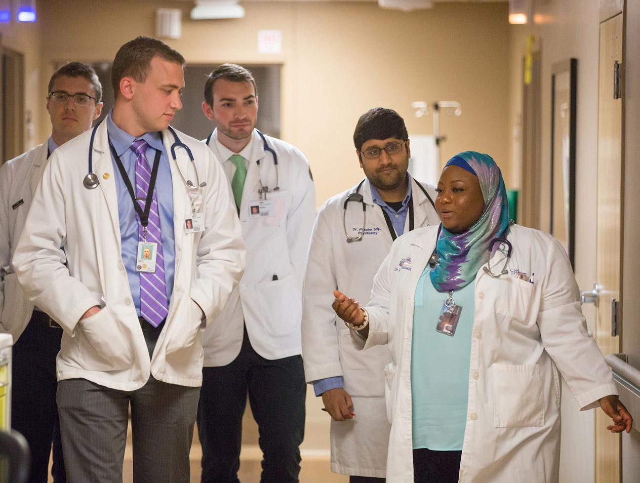A group of medical students walking and talking with their supervising doctor