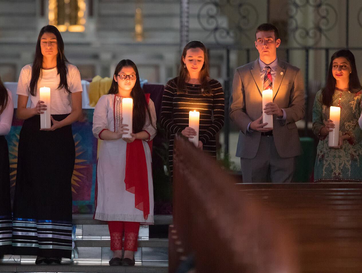 Students holding lit candles during an Interfaith Prayer Service