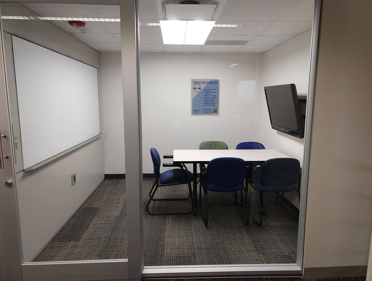 A study room in the Health Sciences Library with a table, chairs, whiteboard, and monitor