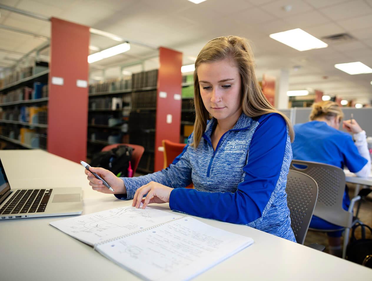 A female student doing research in the library