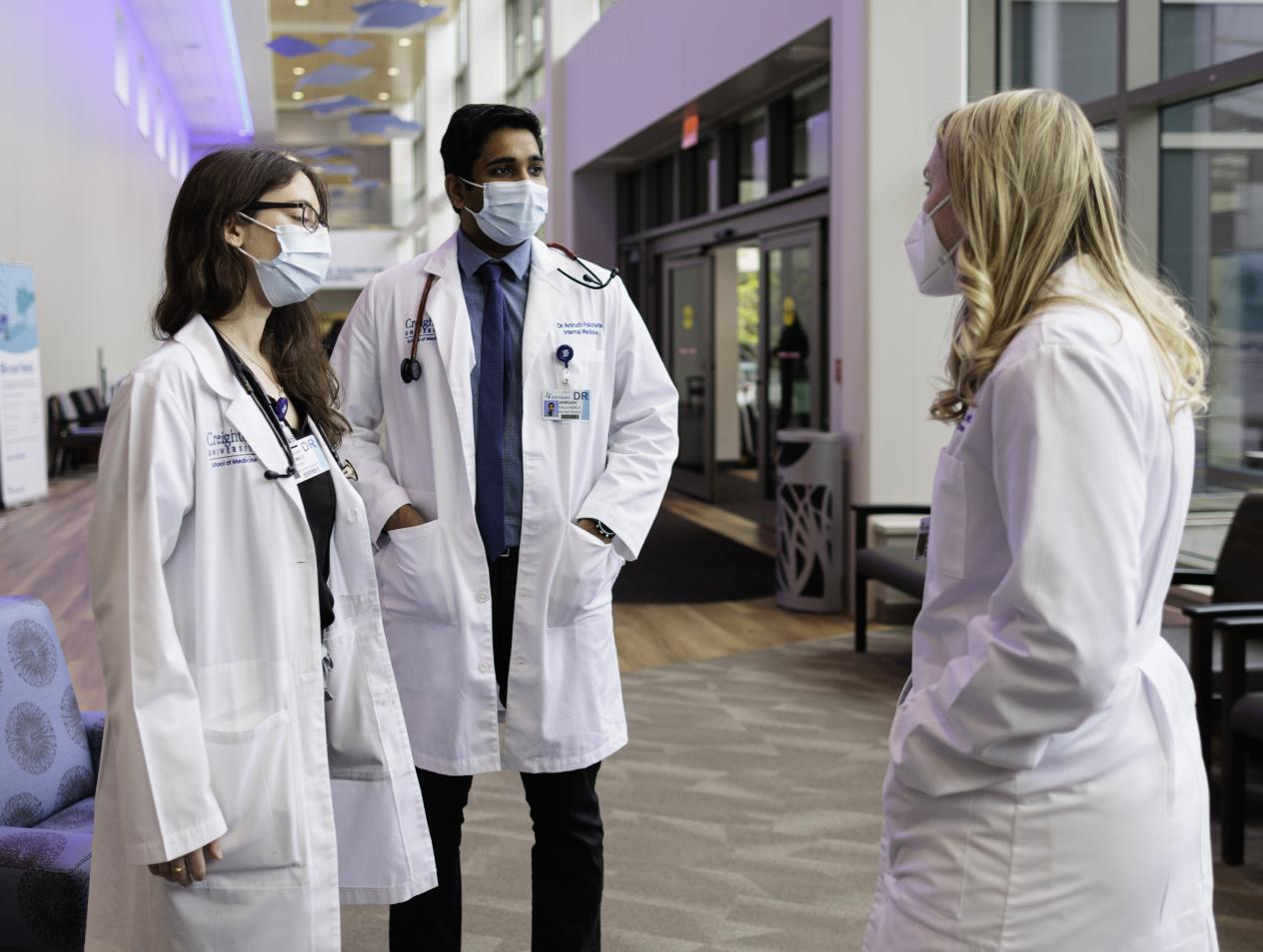 Doctors having conversation in hallway wearing white coats.