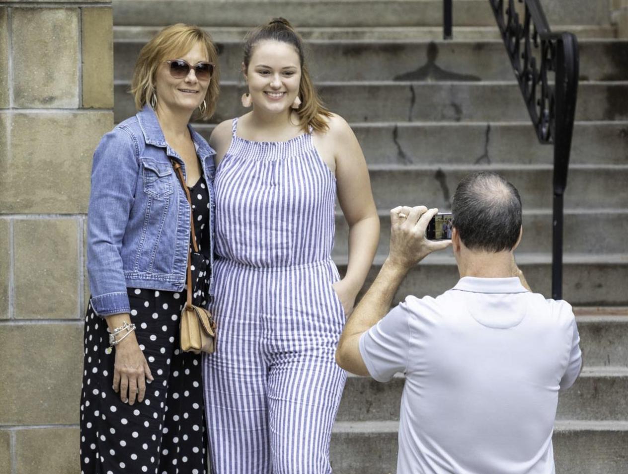 Parents taking photos with daughter on campus.