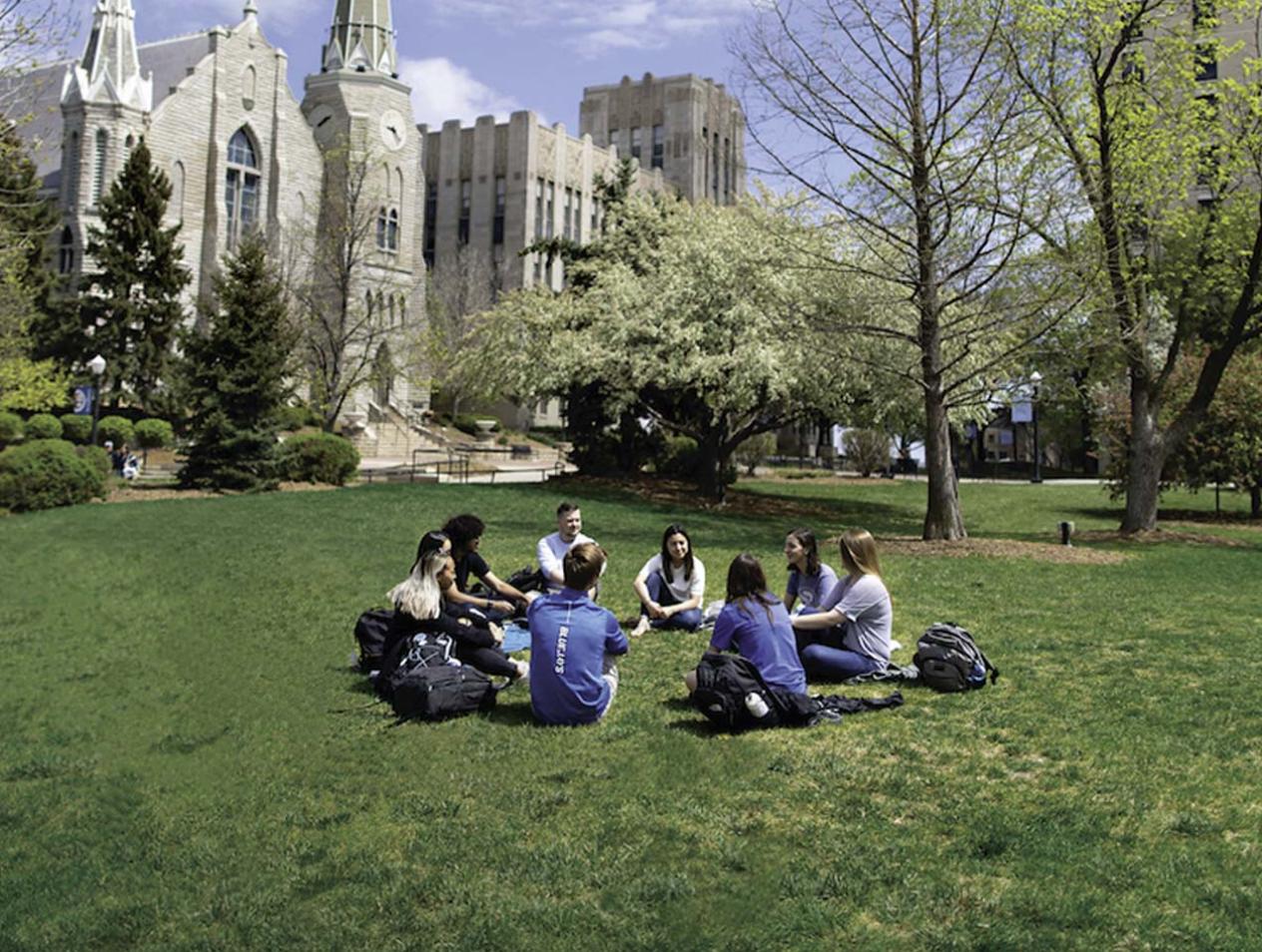Students sitting in circle on campus green space.