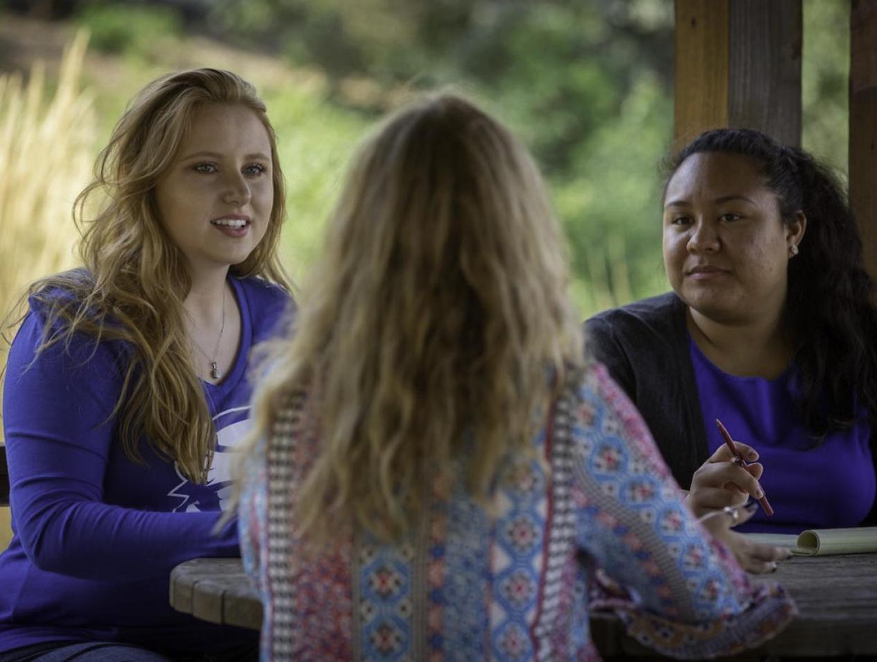Three students talking at outside table