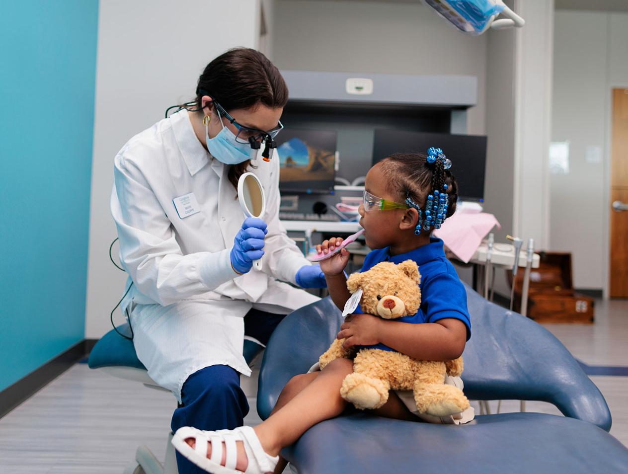 Dental student showing child her teeth with a mirror