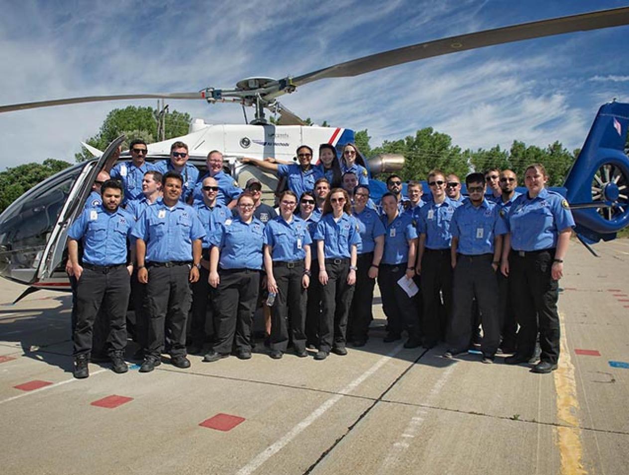 Group of critical care transport professionals standing in front of a medical transport helicopter