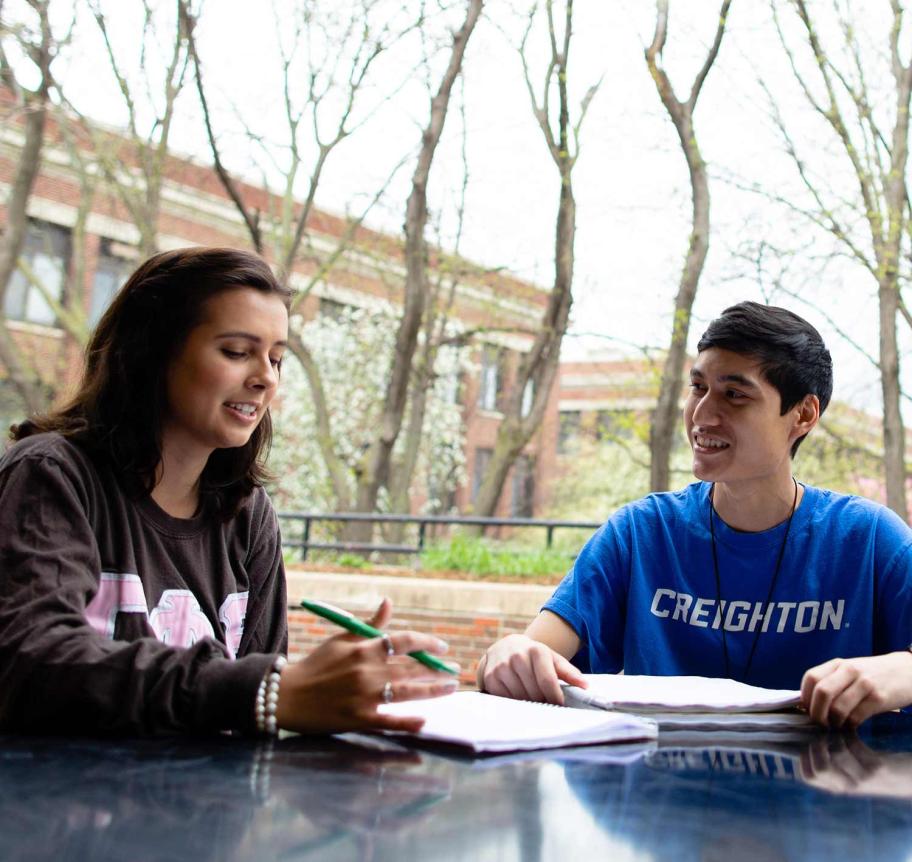 Students sitting outside at table studying