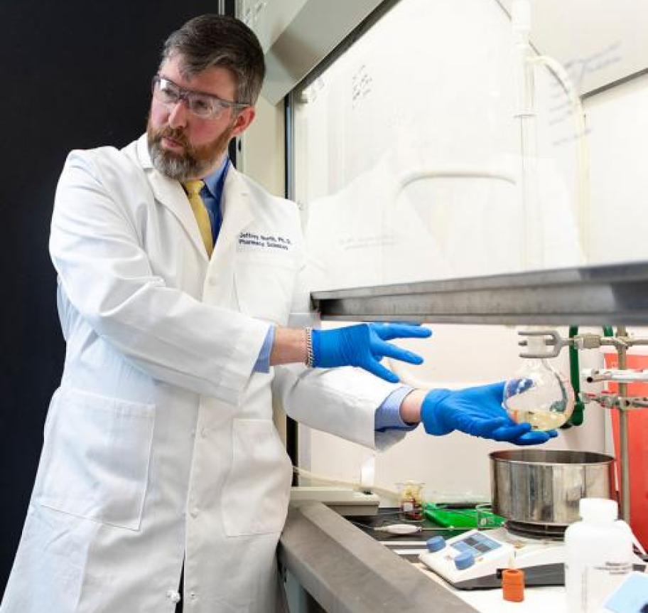 A scientist in a lab gesturing to a beaker
