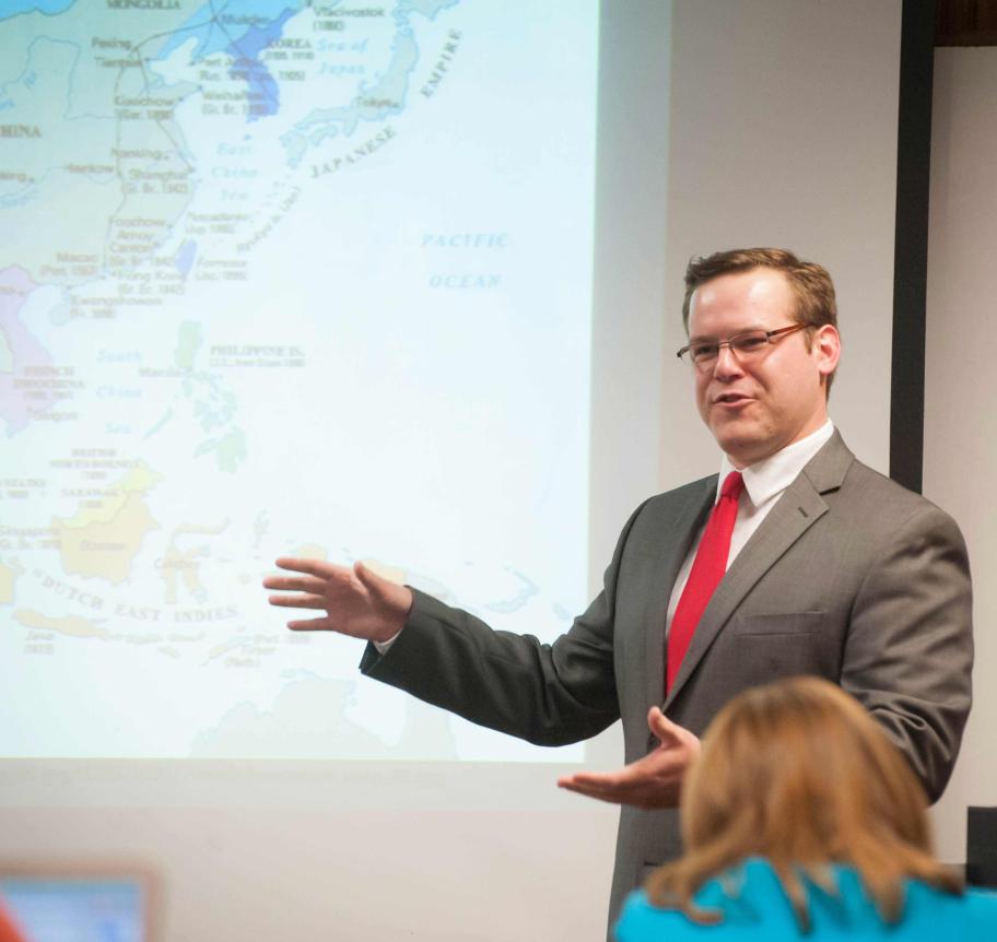 Creighton faculty teaching in classroom with map of Asia on screen