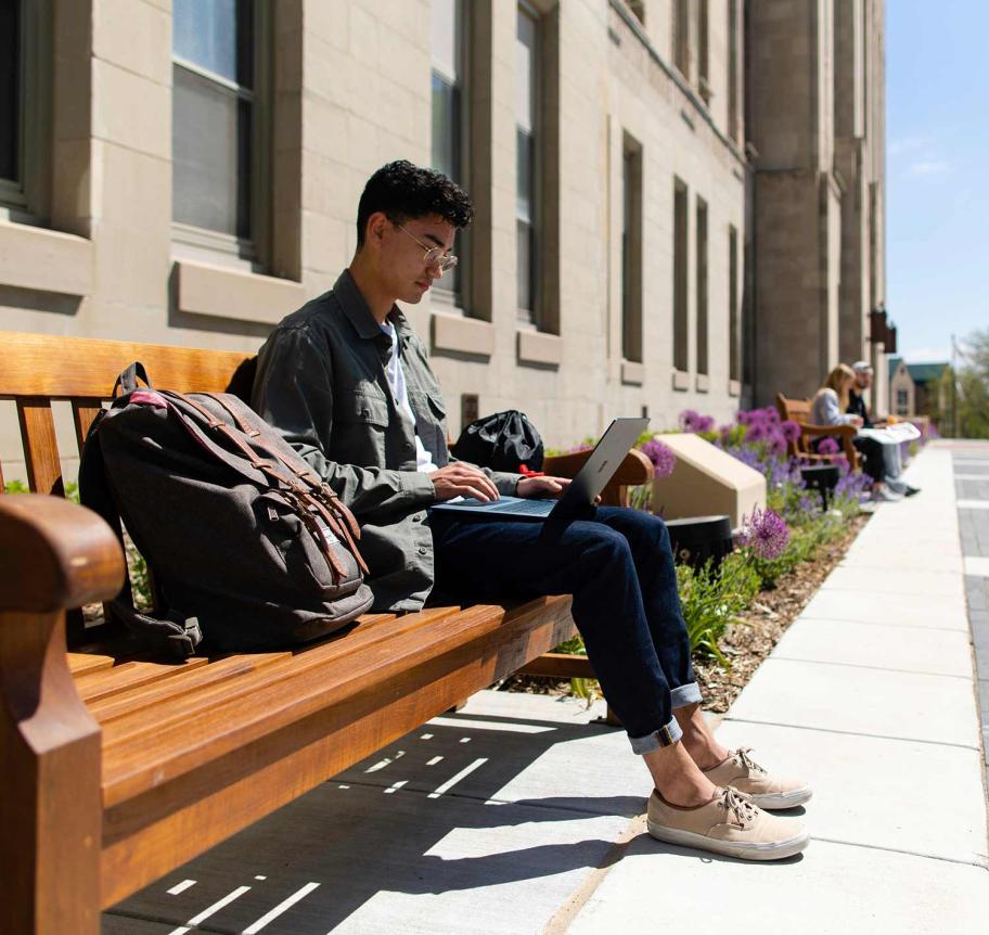 Student on bench outdoors on Creighton campus