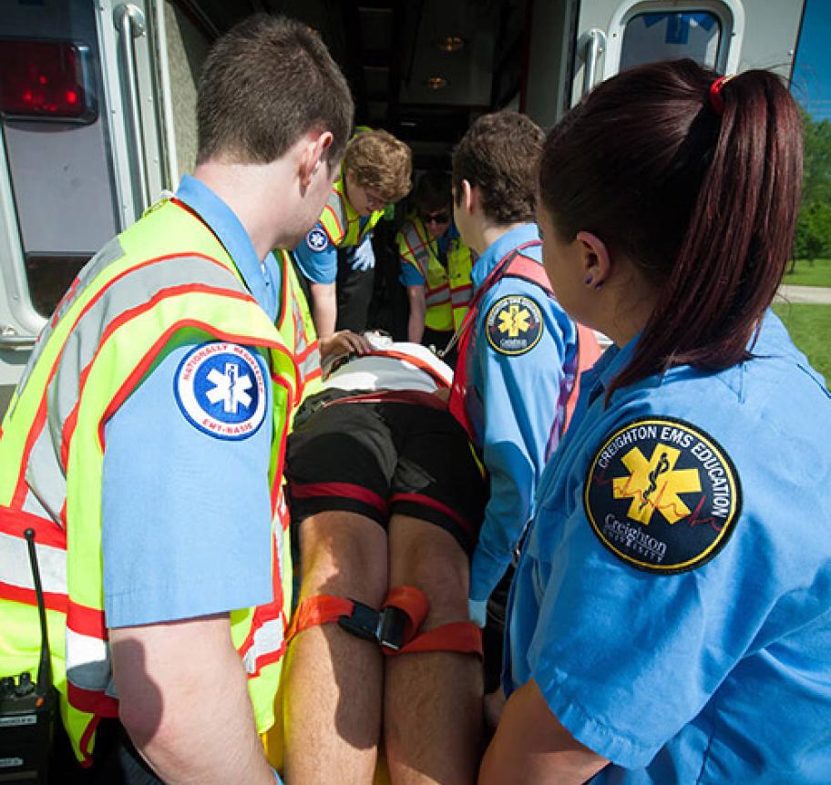 EMT students loading a patient on a stretcher into an ambulance