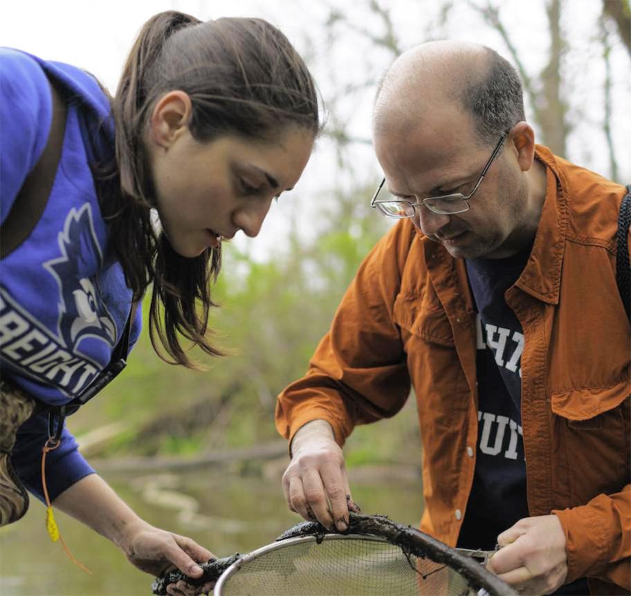 Biology professor John Shea censusing a stream with a student 