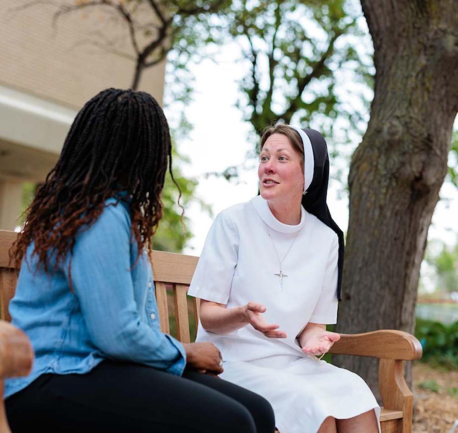 Nun talking to student on campus.