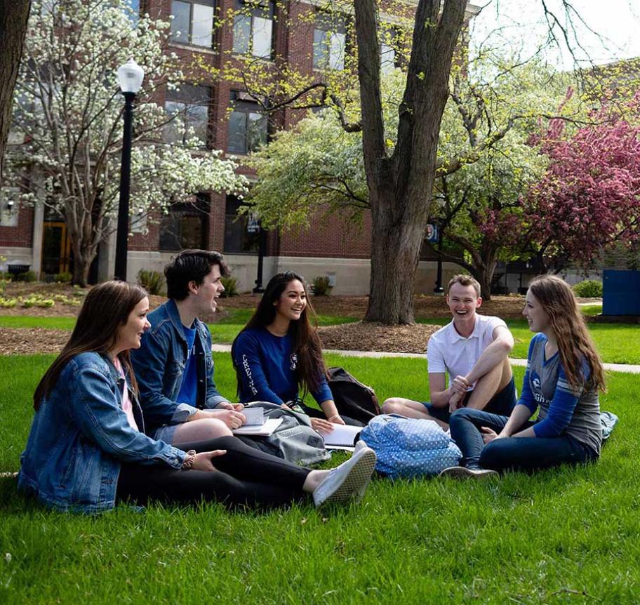 Creighton students sitting outdoors on campus lawn