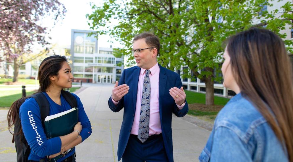 Administrator speaking with pair of students on campus