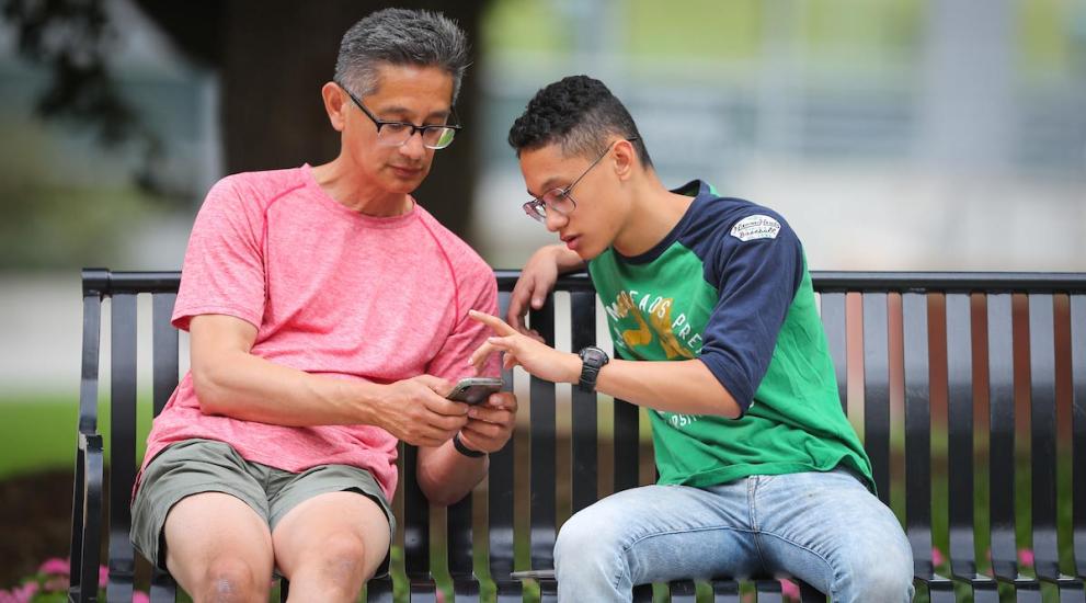 Parent with student on Creighton campus helping child to find information on their phone.