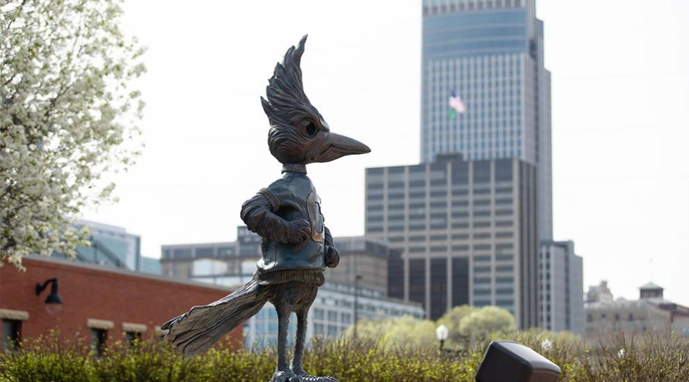 Billy Bluejay statue in front of Omaha skyline