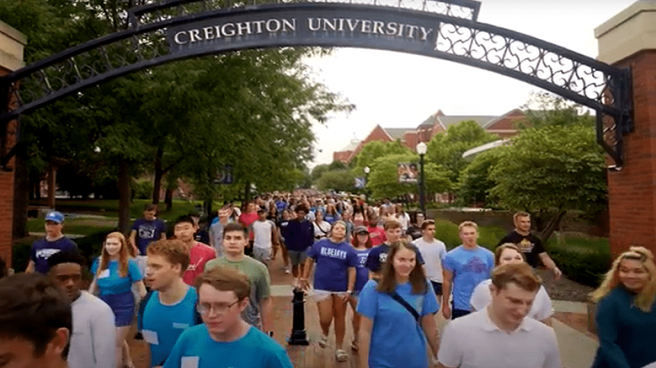 Students walking in mass underneath Creighton arc