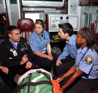 Paramedic students listening to their instructor in the back of an ambulance