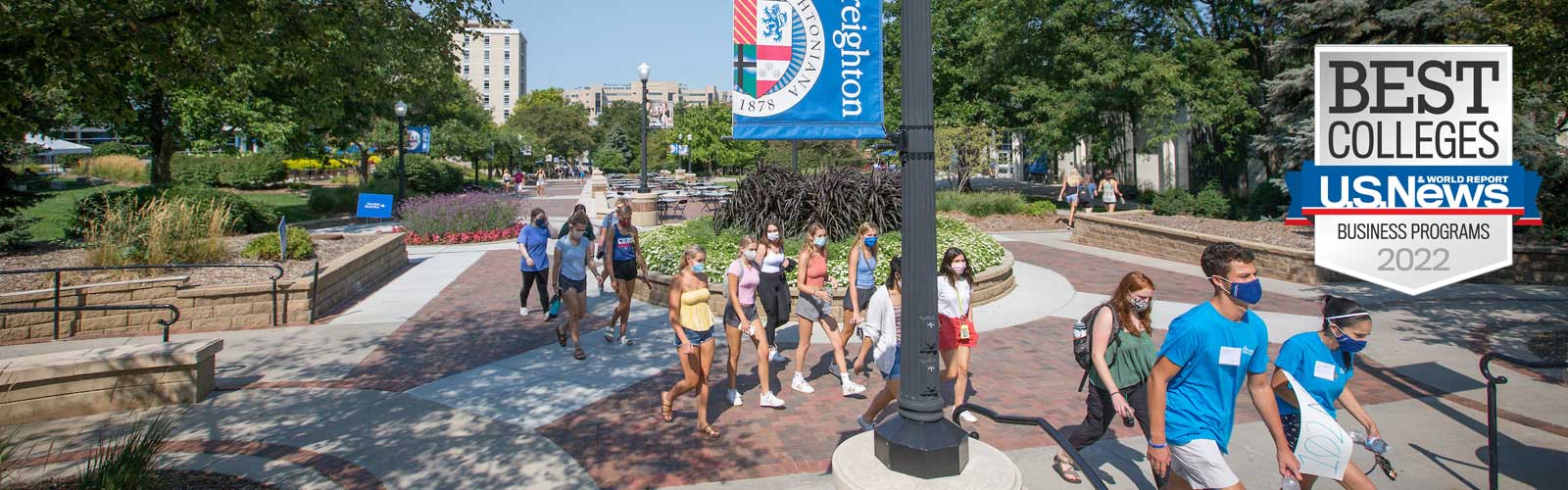 Students walking across campus with the U.S. News & World Report Best Colleges - Business Programs 2022 badge overlaid