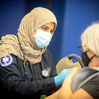 Marj Alhumayed, EMS student, giving a covid vaccine to a patient