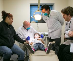 Several dentists with mother examining child