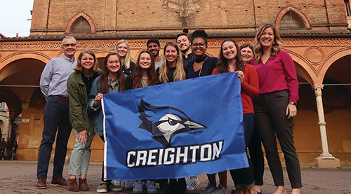 A group of students and faculty holding up a Creighton flag during a study abroad trip