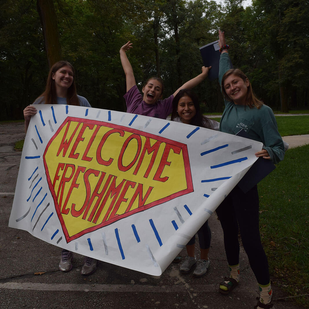 Four female students holding a banner that says Welcome Freshmen