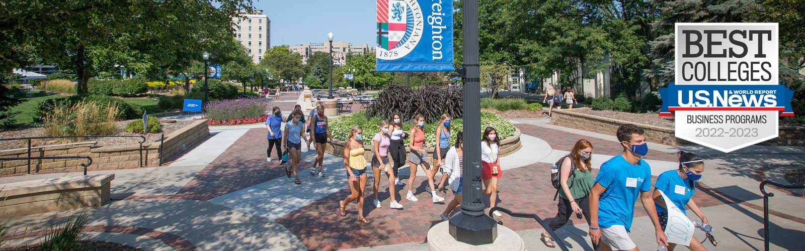 Students walking across campus with the U.S. News & World Report Best Colleges - Business Programs 2022-2023 badge overlaid