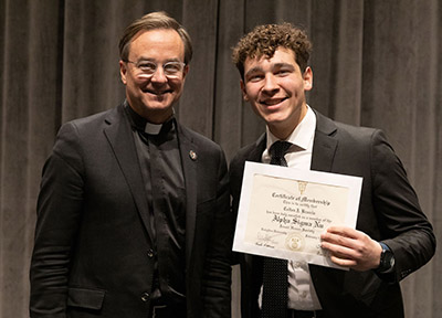 CJ Braccia with Father Hendrickson while receiving Alpha Sigma Nu certificate. 