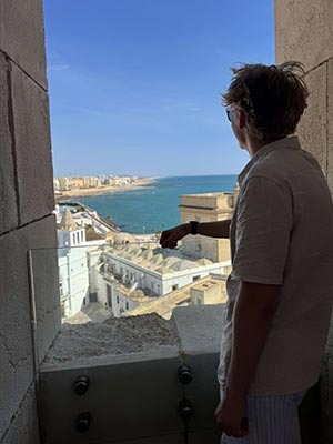 Jake looking out window over Spanish coastal town