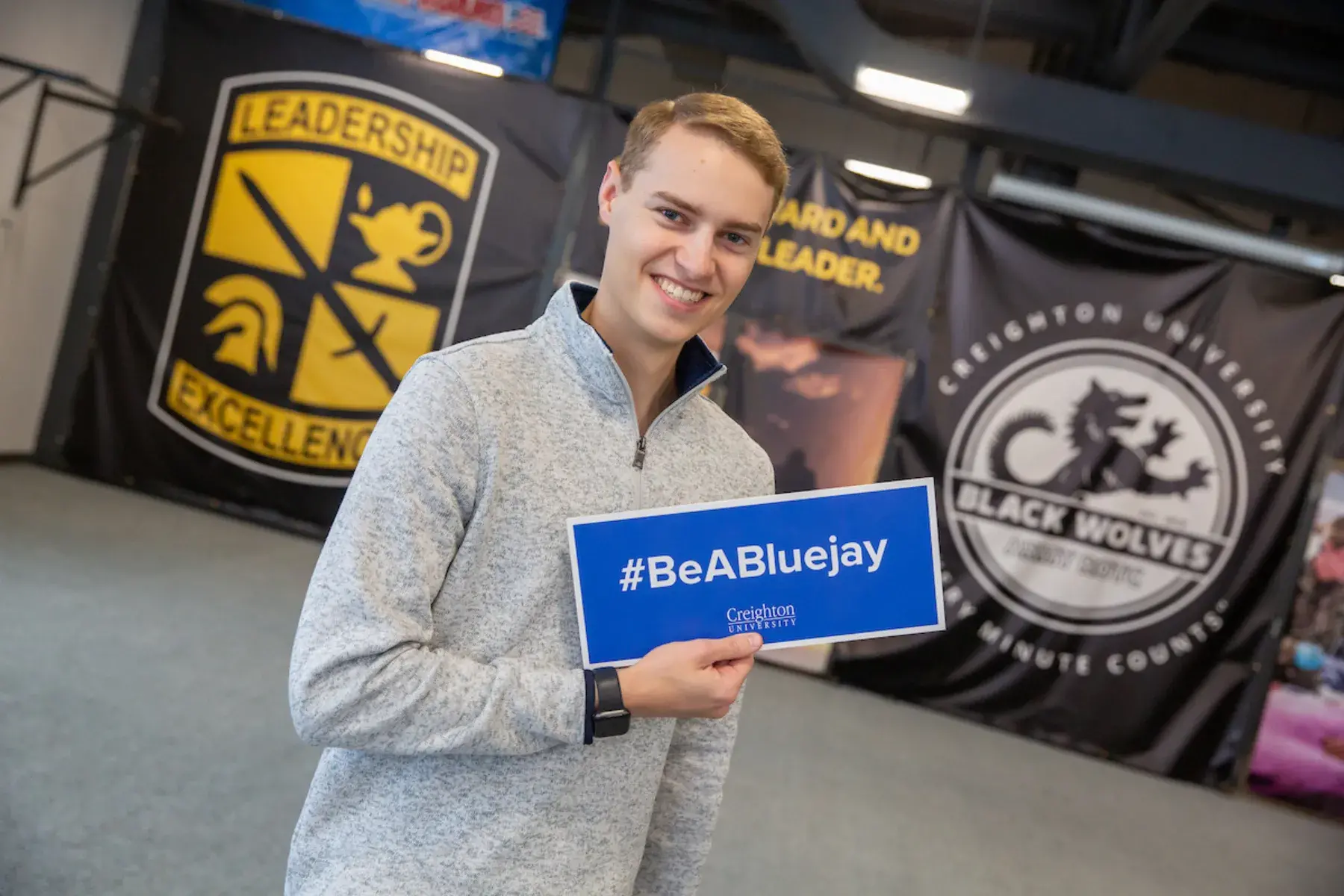 Austin Roeder with sign that reads "Be a Bluejay"