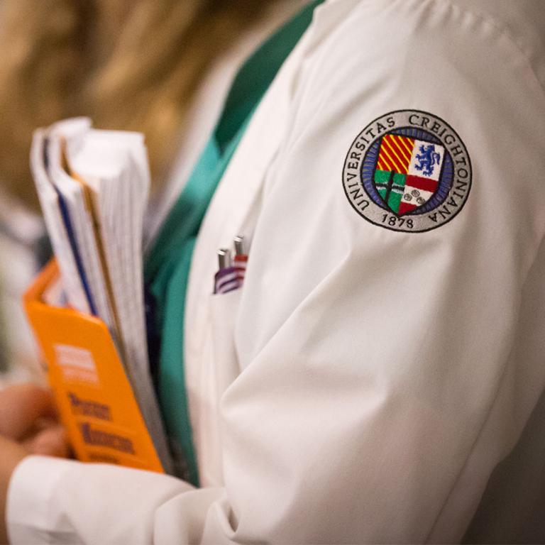 Closeup of the Creighton University crest on the sleeve of a medical student's white coat