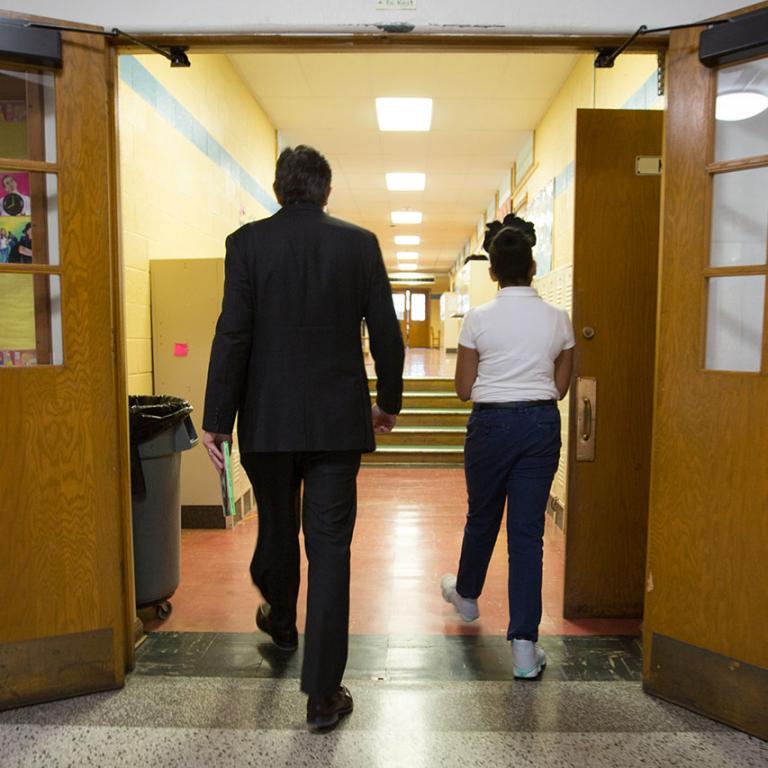 A teacher and a student walking down a school hallway