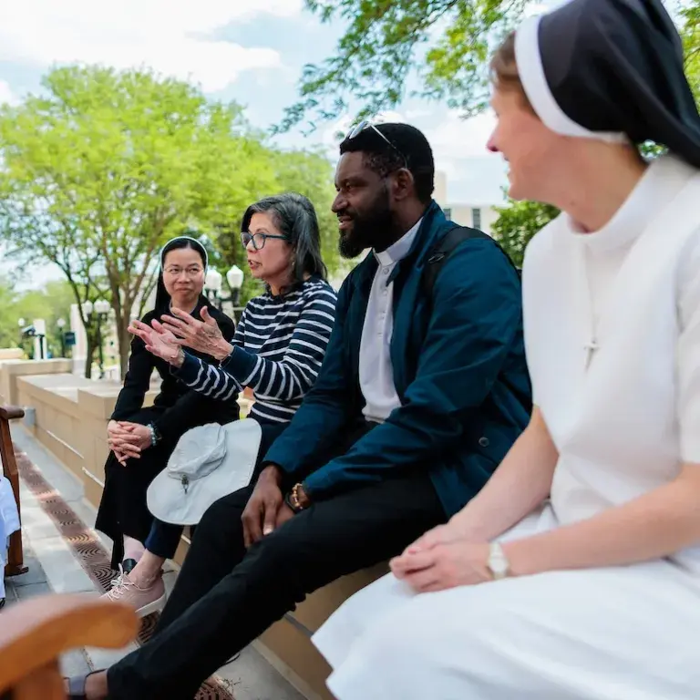 Group of four adults sitting outside talking.