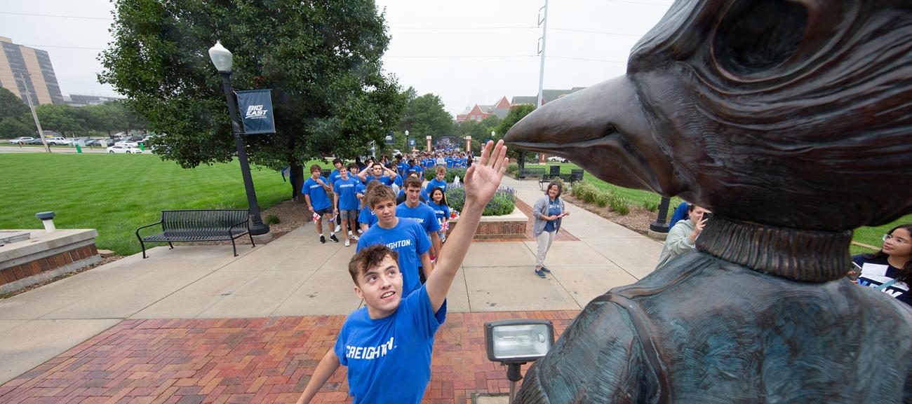 Creightons student touches BIlly Bluejay's beak