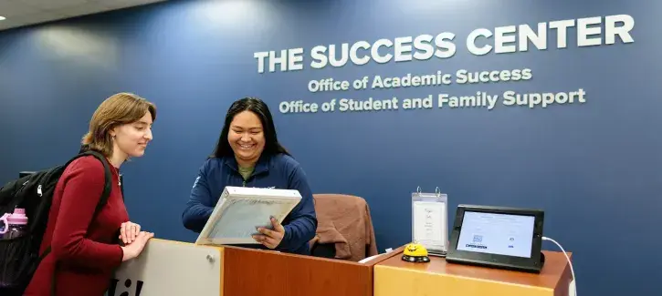Student works with staff at Success Center desk.
