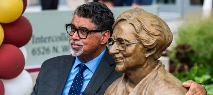 Littleton Alston sits next to a bronze statue of Sister Jean Dolores