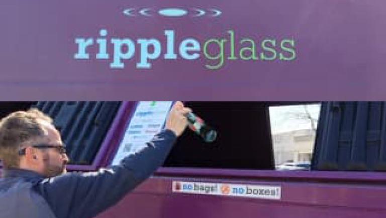 A man placing glass in a recycling bin