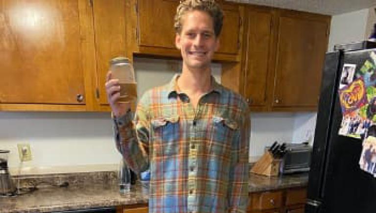 Nick McCreary holding a jar of homemade vegetable broth