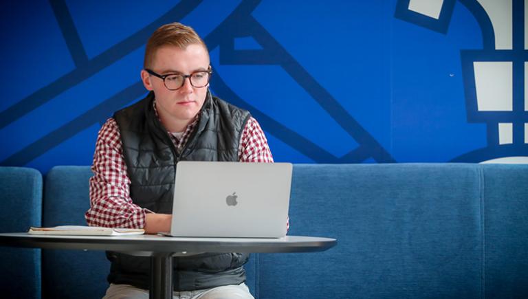 Student on laptop in Creighton Heider Business College study area.
