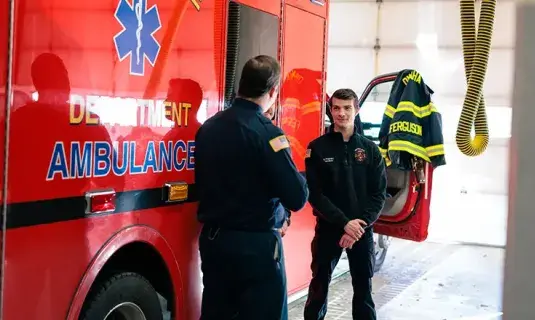 Two paramedics talking beside ambulance.