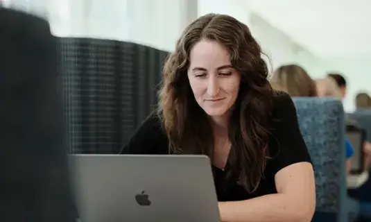 Nursing student studying on laptop in communal space.