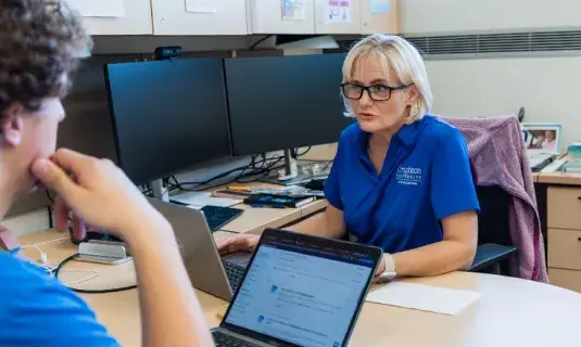 Librarian assisting a student at their desk.