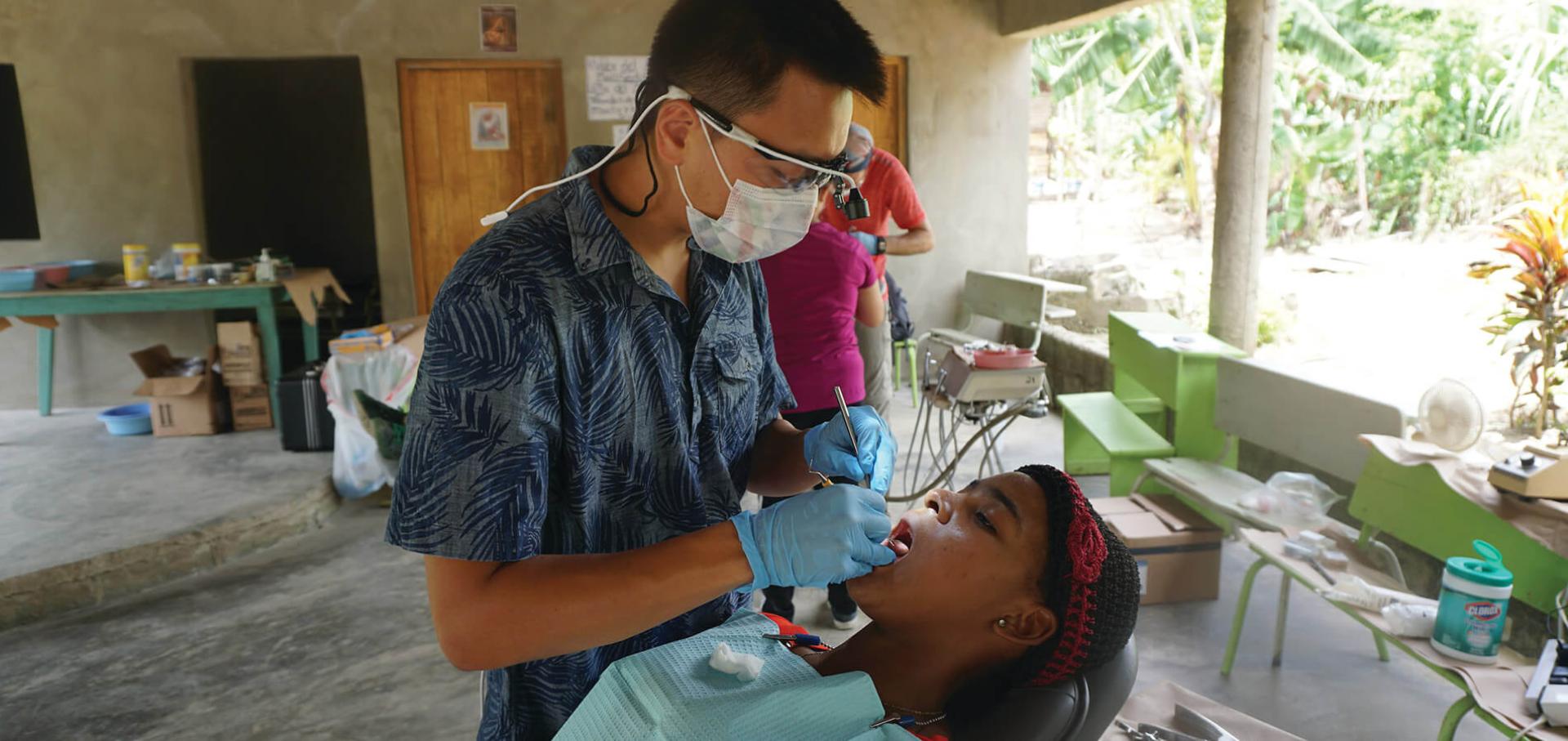 A dentist performs a checkup on a young girl during a service trip
